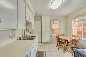 Kitchen with white cabinetry, sink, and light tile patterned floors