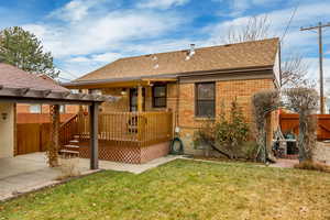 Rear view of house with a wooden deck, a pergola, central air condition unit, and a lawn