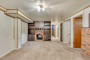 Unfurnished living room featuring light carpet and a wood stove