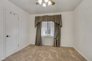 Empty room with light colored carpet and ceiling fan