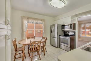 Kitchen with white cabinetry, light tile patterned floors, stainless steel appliances, and sink