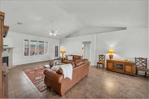 Living room with ceiling fan, lofted ceiling, and a high end fireplace