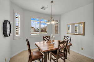 Tiled dining space featuring plenty of natural light and a chandelier