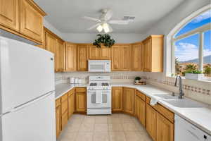 Kitchen featuring light tile patterned flooring, sink, tasteful backsplash, a mountain view, and white appliances