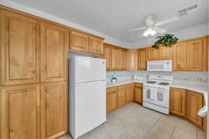 Kitchen featuring ceiling fan, white appliances, backsplash, and light tile patterned floors