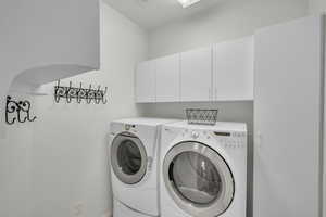 Washroom with cabinets and independent washer and dryer