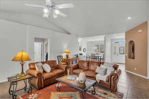 Living room with lofted ceiling, tile patterned floors, and ceiling fan