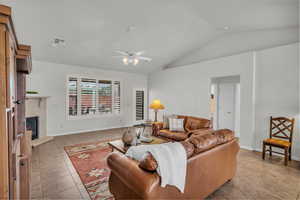 Tiled living room with a premium fireplace, lofted ceiling, and ceiling fan