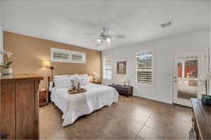 Tiled bedroom with access to outside, a textured ceiling, and ceiling fan