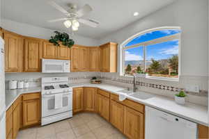 Kitchen featuring sink, tasteful backsplash, light tile patterned floors, ceiling fan, and white appliances