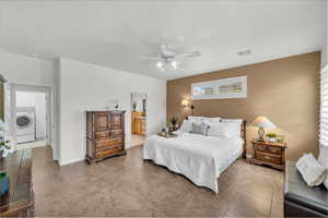 Tiled bedroom with ceiling fan, washer / dryer, and ensuite bath