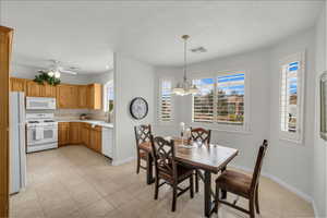 Dining area featuring light tile patterned floors, ceiling fan with notable chandelier, and sink