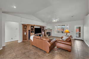 Living room with vaulted ceiling, a tile fireplace, and ceiling fan