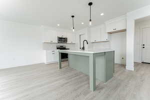 Kitchen with tasteful backsplash, light wood-style floors, stainless steel appliances, and light countertops