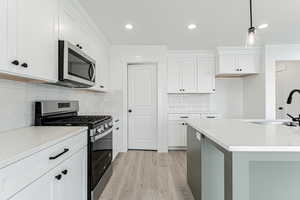 Kitchen featuring recessed lighting, appliances with stainless steel finishes, white cabinets, light wood finished floors, and a sink