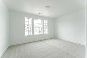 Carpeted spare room featuring a textured ceiling, visible vents, and baseboards