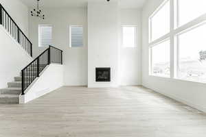 Unfurnished living room featuring visible vents, wood finished floors, a notable chandelier, and stairs