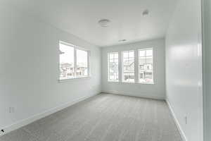 Spare room with a textured ceiling, baseboards, and light carpet