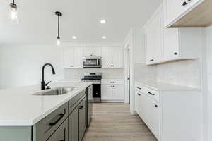 Kitchen featuring white cabinets, a sink, appliances with stainless steel finishes, light wood-type flooring, and recessed lighting