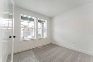 Carpeted empty room with visible vents and baseboards