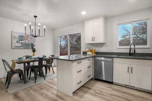 Kitchen with sink, hanging light fixtures, light wood-type flooring, kitchen peninsula, and dishwasher