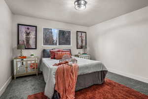 Bedroom featuring dark carpet and a textured ceiling