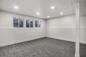 Spare room featuring dark carpet and a textured ceiling