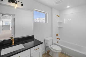 Full bathroom with toilet, hardwood / wood-style floors, vanity, and shower / bathing tub combination