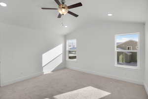 Empty room featuring a healthy amount of sunlight, vaulted ceiling, and light carpet