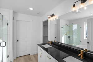 Bathroom with a shower with door, wood-type flooring, and vanity