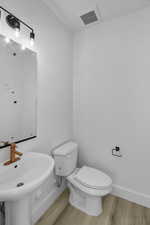 Bathroom with wood-type flooring, toilet, and sink