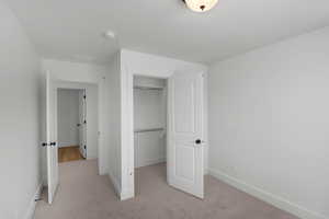 Unfurnished bedroom featuring a closet and light carpet