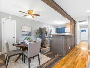 Dining room with beamed ceiling, ceiling fan, and light hardwood / wood-style flooring