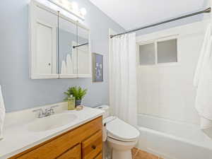 Full bathroom with tile patterned flooring, vanity, shower / bath combo, and heated bidet toilet with remote settings