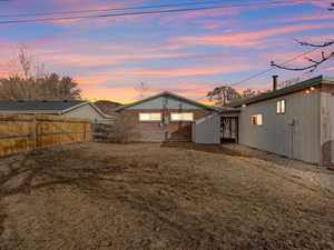 Back house at dusk featuring a lawn