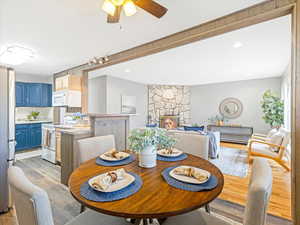 Dining space featuring ceiling fan, a fireplace, and light hardwood / wood-style floors