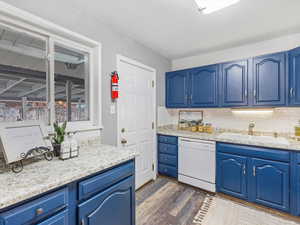 Kitchen featuring sink, decorative backsplash, dishwasher, and blue cabinets