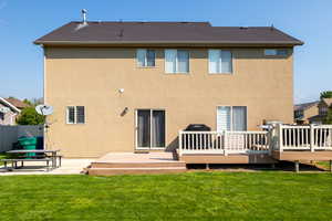 Back of property with a wooden deck, a yard, and a patio area