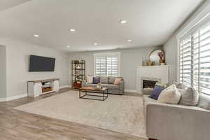 Living room with a tiled fireplace and hardwood / wood-style floors