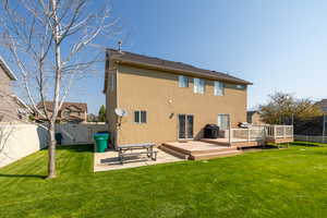 Back of property with a wooden deck, a yard, and a patio area