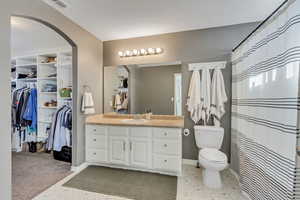 Bathroom featuring a shower with curtain, vanity, and toilet