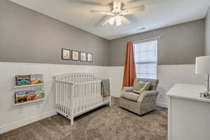 Bedroom with a nursery area, ceiling fan, and carpet