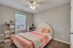 Bedroom with ceiling fan and dark carpet