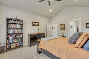 Bedroom featuring vaulted ceiling, light colored carpet, ensuite bathroom, and ceiling fan