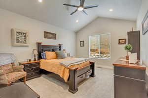 Carpeted bedroom featuring ceiling fan and vaulted ceiling