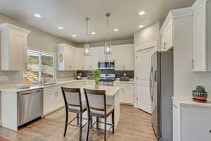 Kitchen featuring white cabinetry, sink, stainless steel appliances, and a kitchen island