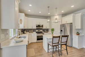 Kitchen featuring sink, white cabinetry, stainless steel appliances, tasteful backsplash, and light hardwood / wood-style floors