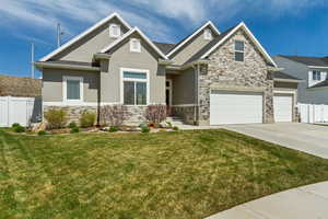 Craftsman house with stucco siding, fence, stone siding, a front lawn, and concrete driveway