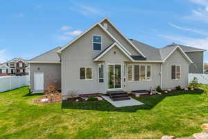 Rear view of house with a yard, roof with shingles, fence, and stucco siding
