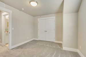 Unfurnished bedroom featuring light colored carpet and a closet